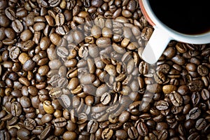 Roasted coffee beans and a cup with coffee