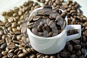 Roasted coffee beans and cup on the wooden background