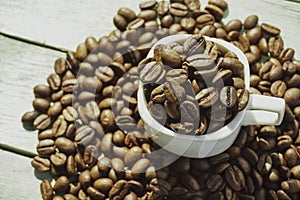 Roasted coffee beans and cup on the wooden background