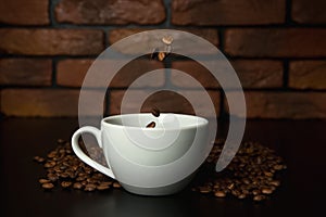 Roasted coffee beans falling into cup.