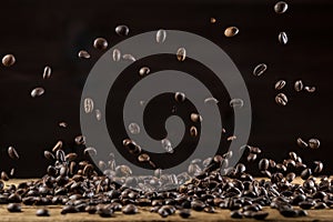 Roasted coffee beans falling down on wooden table