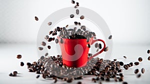 Roasted coffee beans, falling into a red coffee cup, on white background