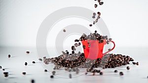 Roasted coffee beans, falling into a red coffee cup, on white background