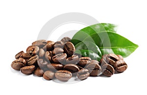 Roasted coffee beans and fresh green leaves on white