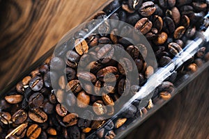 Roasted coffee beans in a glass bottle on a wooden table top view macro photo