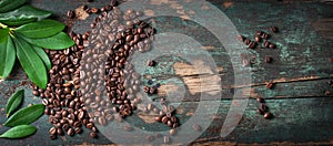 Roasted coffee beans with green leaves on a vintage background