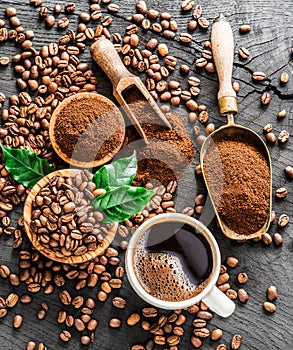Roasted coffee beans, ground coffee and cup of coffee on wooden