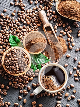 Roasted coffee beans, ground coffee and cup of coffee on wooden