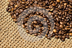 Roasted coffee beans on a knitted pattern in beige raffia. Hand knitted