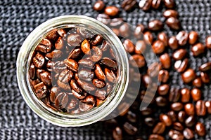 Roasted coffee beans, medium roasted in the glass bottle and on the black net.