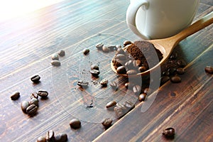 Roasted coffee beans mix ground coffee on wooden spoon , roasted coffee beans on retro wood floor