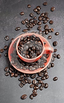 Roasted coffee beans in a red cup on black background.