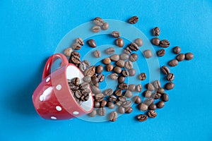 Roasted coffee beans in a red cup on a blue background close-up