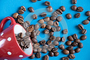 Roasted coffee beans in a red cup on a blue background close-up
