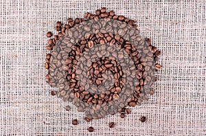 Roasted coffee beans on sack fabric background