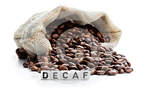Roasted coffee beans scattered out of the bag. Concept of decaf coffee