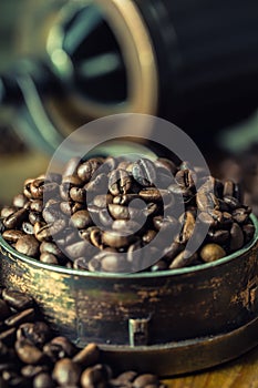 Roasted coffee beans spilled freely on a wooden table. Coffee beans in a dish for ground coffee.