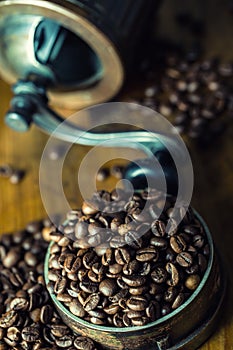 Roasted coffee beans spilled freely on a wooden table. Coffee beans in a dish for ground coffee.