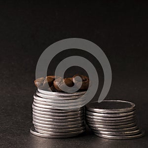 Roasted coffee beans on a stack of metal coins