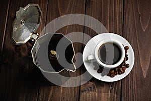 Roasted coffee beans with a white cup of espresso on a dark wooden table, rustic, top view