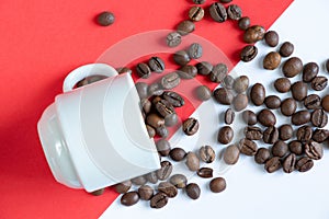 Roasted coffee beans and white cup on red and white background close-up