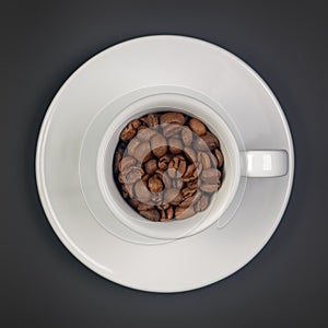 Roasted coffee beans in a white Cup and saucer