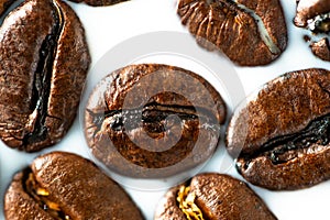 Roasted coffee beans on white milk background. Coffee beans in milk. Top view macro shot of arabica, robusta and iberica coffee se