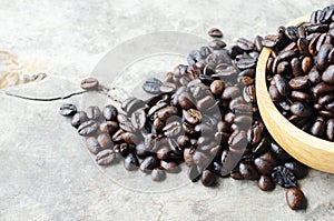 Roasted coffee beans in wooden bowl on dark vintage wood table background
