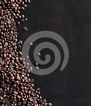 Roasted coffee beans on a wooden dark table, top view