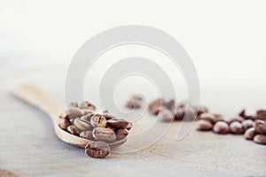 Roasted coffee beans on a wooden table with wooden spoon on a white background, isolated, close up