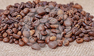 Roasted coffee on burlap. Aromatic coffee beans macro photo