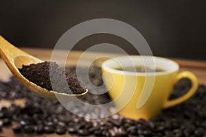 Roasted coffee on wooden spoon with coffee beans and yellow mug photo