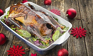 Roasted duck with fresh herbs in a ceramic baking sheet is served on a festive Christmas table. Side view, close-up