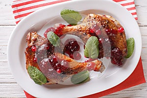 roasted duck leg with cranberry sauce and mint closeup. horizontal top view