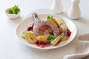 Roasted duck leg with a[[les and cranberry sauce close up
