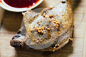 Roasted Duck Leg with Spices, Lemon Juice, Mustard and Berry Sauce on Dark Background