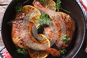 Roasted duck legs in a pan with oranges top view horizontal