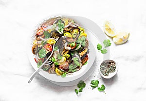 Roasted eggplant, sweet tomato and cilantro mediterranean style salad on light background, top view. Vegetarian food