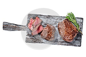 Roasted fillet mignon or tenderloin beef steak on wooden cutting board. Isolated on white background, top view.