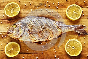Roasted gilt head bream fish on a wooden table.