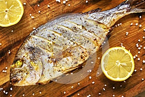 Roasted gilt head bream fish on a wooden table.