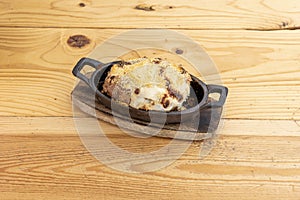 Roasted and gratin potato with bÃ©chamel sauce and grated cheese inside an individual cast iron container