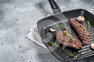 Roasted on a grill skillet Flank flap or Bavette beef meat steak with rosemary. Gray background. Top view. Copy space