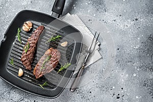Roasted on a grill skillet Flank flap or Bavette beef meat steak with rosemary. Gray background. Top view. Copy space