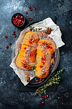 Roasted hasselback butternut squash pumpkin with thyme, pecan and pomegranate. Thanksgiving dinner recipe.