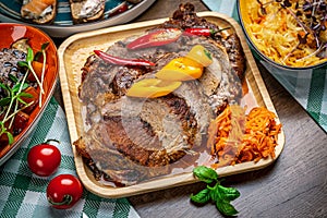 Roasted juicy pork with vegetables on a wooden plate