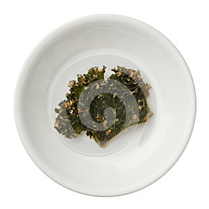Roasted kale chips in a bowl isolated on white background