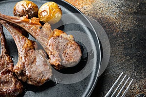 Roasted lamb cutlets ribs with garlic and herbs, on plate, on old dark rustic background , with copyspace  and space for text