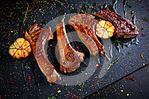 Roasted lamb cutlets ribs with garlic and herbs on stone background