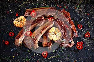 Roasted lamb cutlets ribs with garlic and herbs on stone background